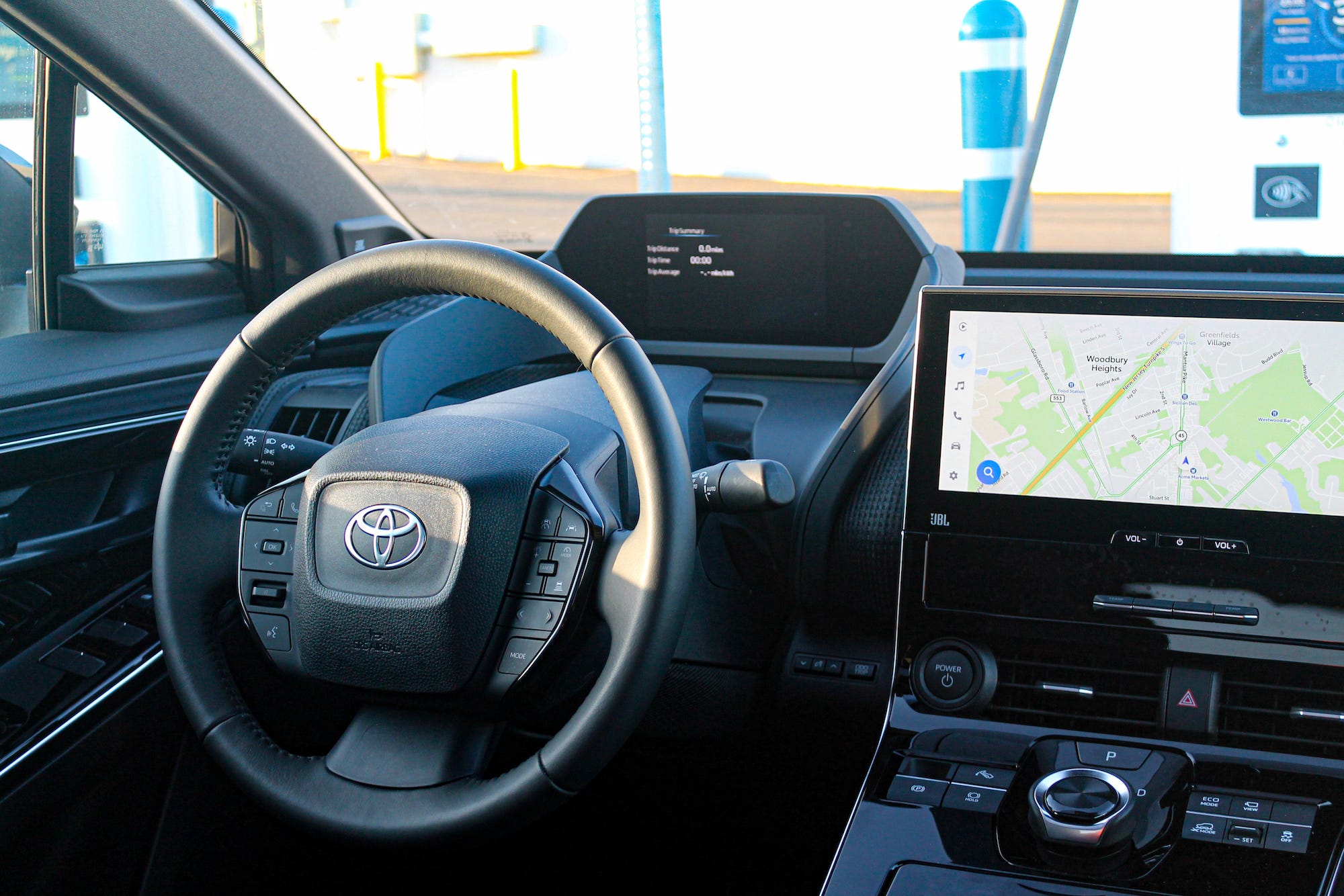 The steering wheel and screens in the 2023 Toyota bZ4X AWD Limited electric SUV, viewed from the back seat.